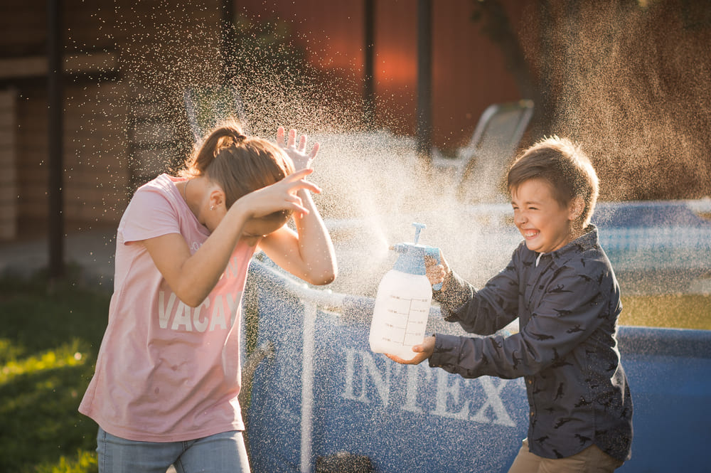 Niño rociando con agua a una niña